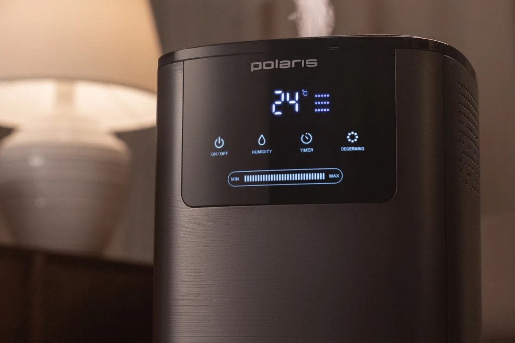 Увлажнитель Polaris PUH 8060 TFD в черном цвете стоит на фоне настольной лампы