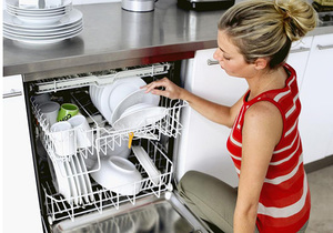Девушка ставит посуду в посудомоечную машину